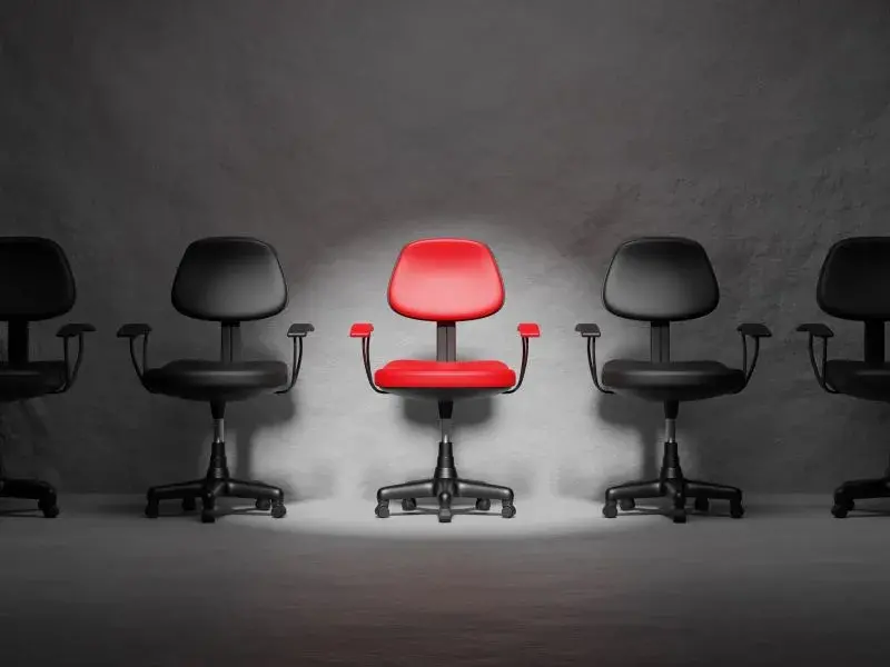 Spotlit red chair amongst black chairs - nflation bonus - Career Guru